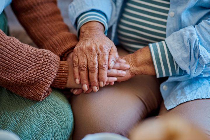 Photo of a couple of people with their hands together on knee