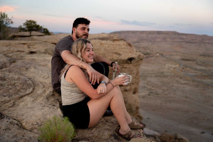 Photo of a couple sitting on a rock formation looking out