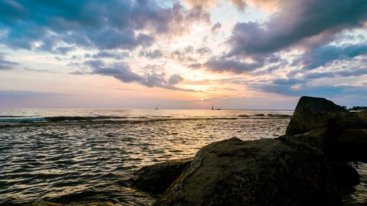 Photo of Lake with setting sunset in clouds and rock formations.