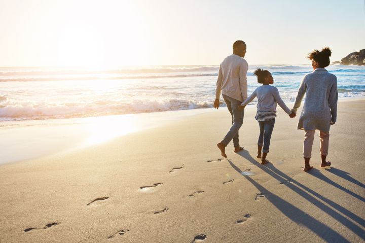 Photo of a couple and a child walking on a beach