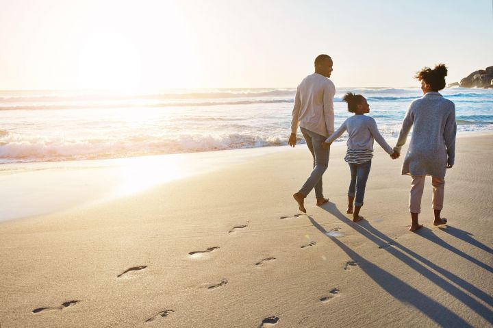 Photo of a couple and a child walking on a beach